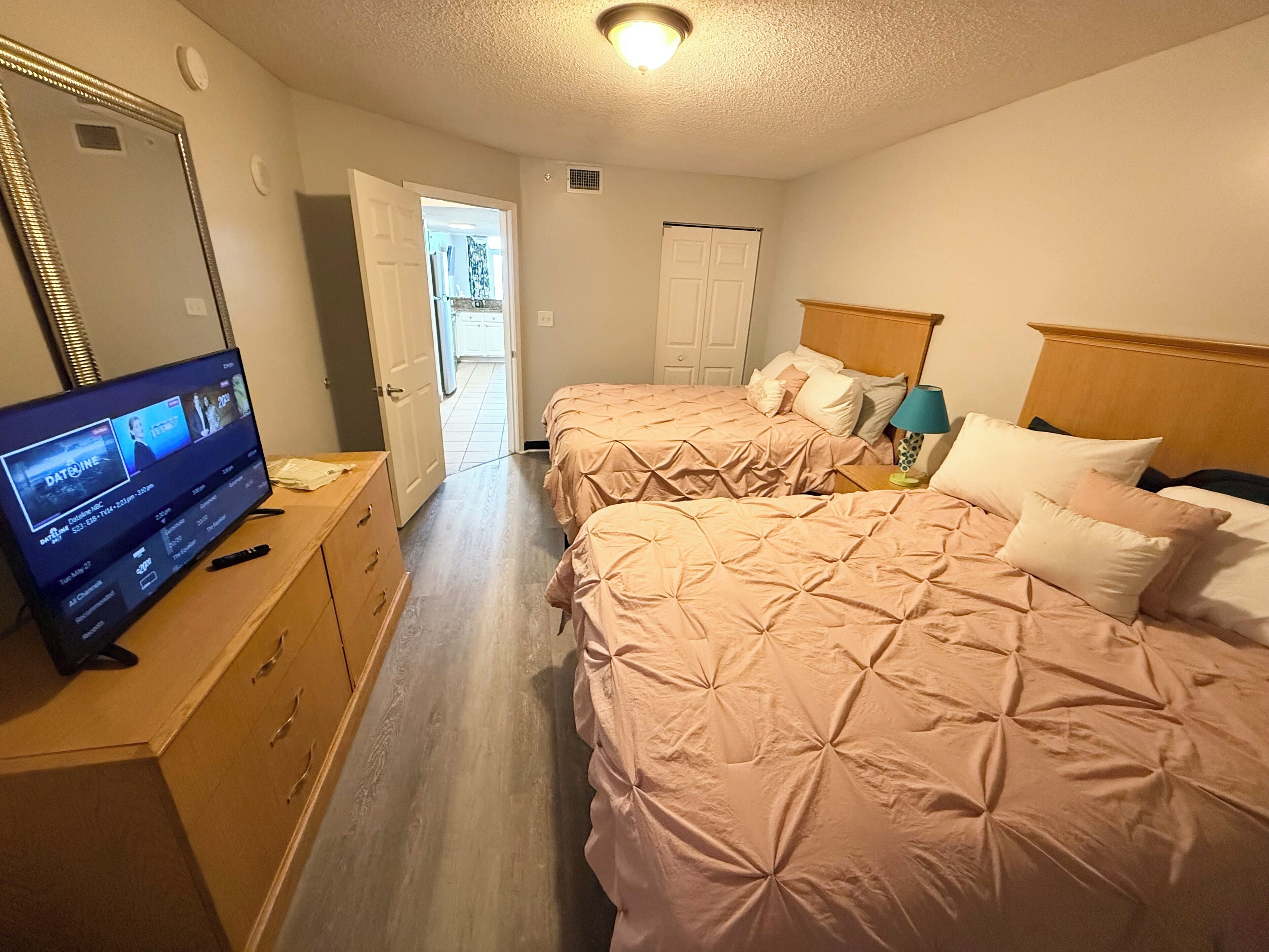 Een hotelkamer met twee bedden, een televisie en een houten dressoir.