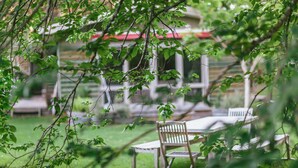 An outdoor seating area with a table and chairs, surrounded by greenery and a building in the background. - Riverdale - An escape from the Yarra Valley (Wesburn)