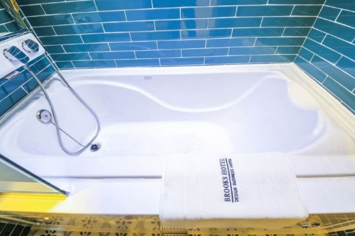 A bathtub with a towel, a showerhead, and a tiled wall.