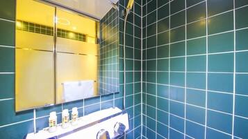 Un baño con azulejos color turquesa, un espejo, toallero y lavamanos con artículos de aseo.