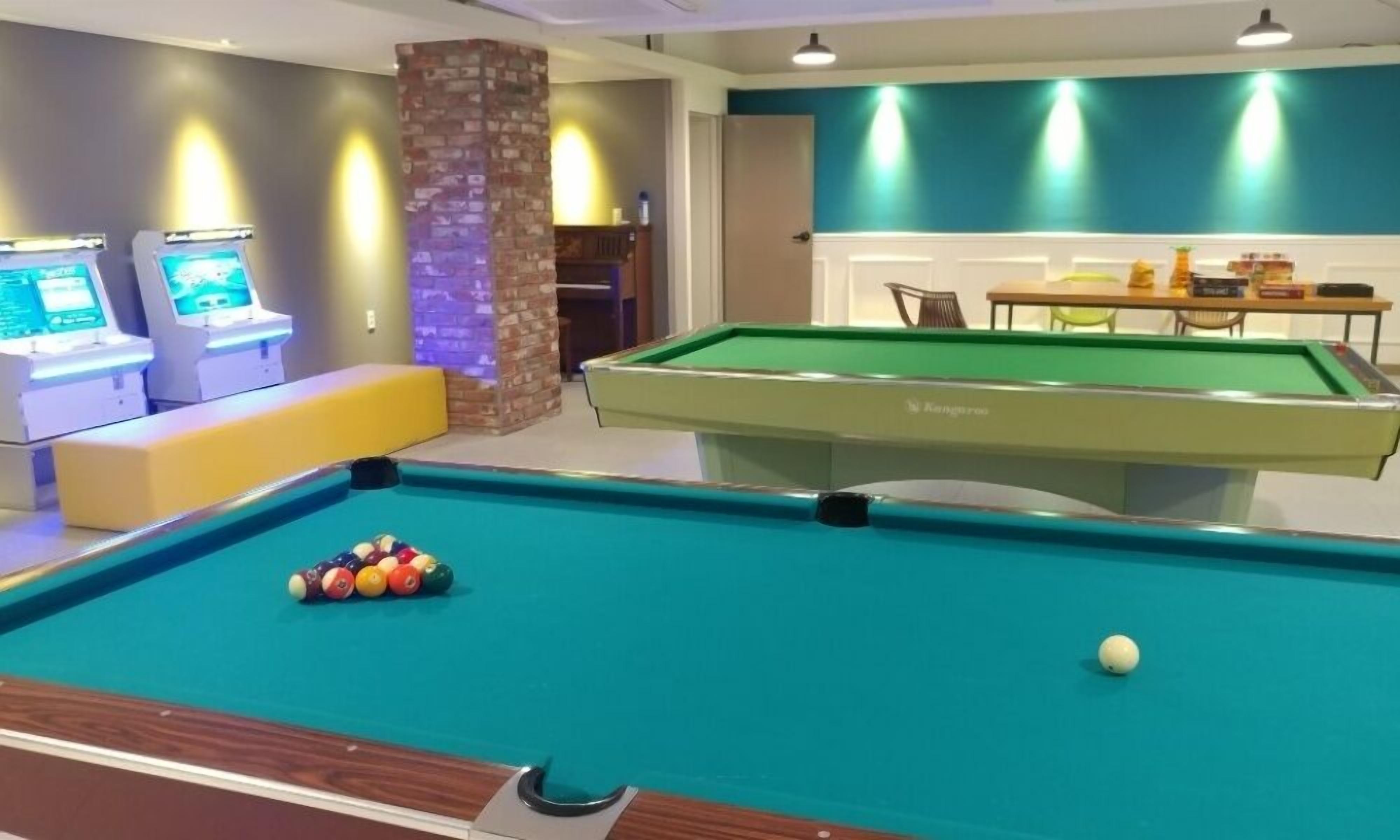 A pool table with balls, a seating area, and a table with chairs.