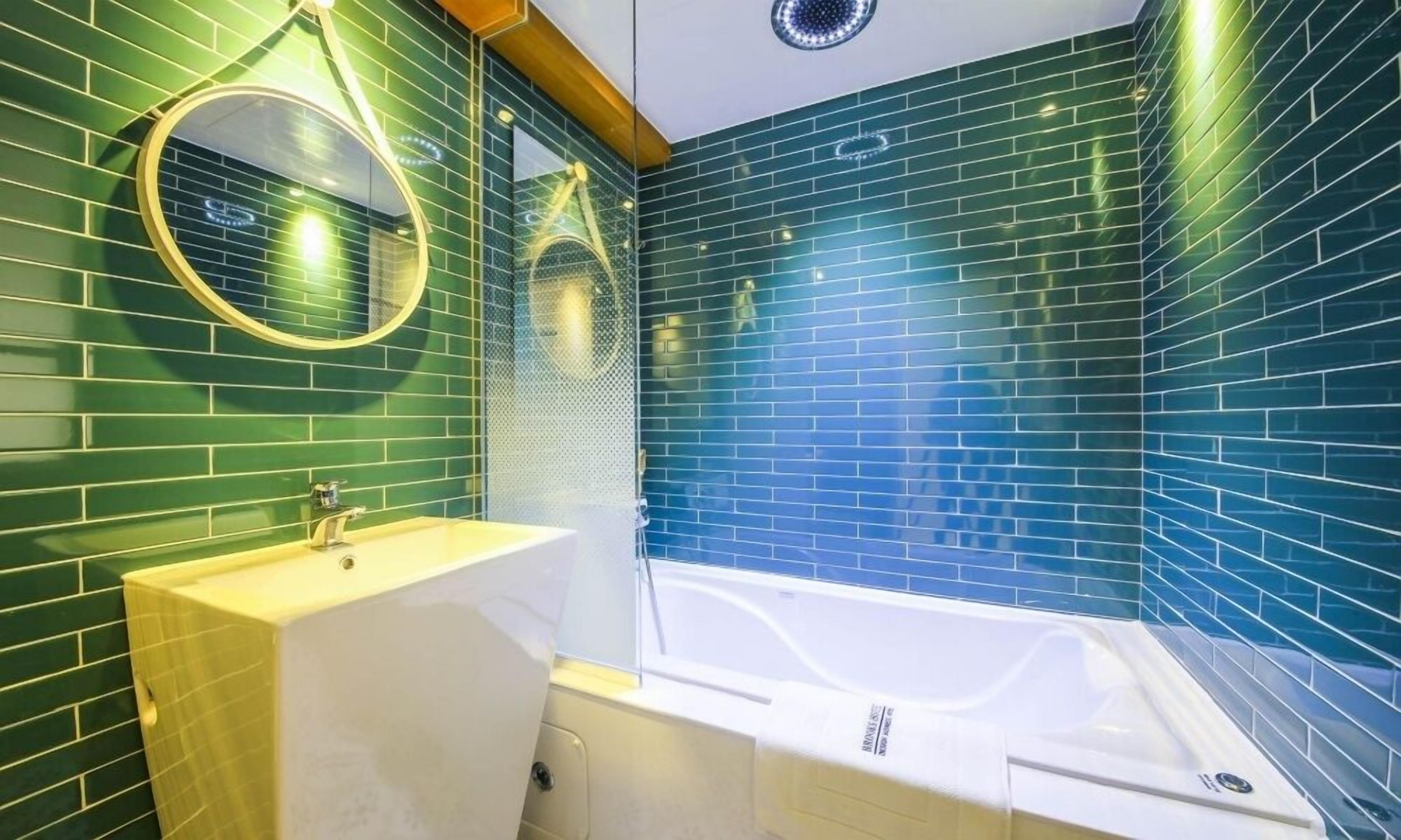 A bathroom with a sink, mirror, and bathtub.