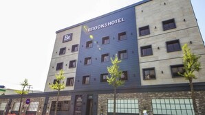 Un hôtel à plusieurs étages, dont la façade porte l’inscription « BROOKSHOTEL », et qui présente une architecture moderne combinant des éléments en brique et en métal.