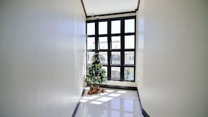 Una habitación con un ventanal grande, un árbol de Navidad y una mesita con adornos.
