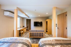 Une chambre d’hôtel avec deux lits, un bureau, une télévision et une armoire.