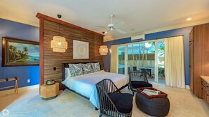Ein Schlafzimmer mit Bett, Deckenventilator, einem Gemälde und Blick ins Freie.