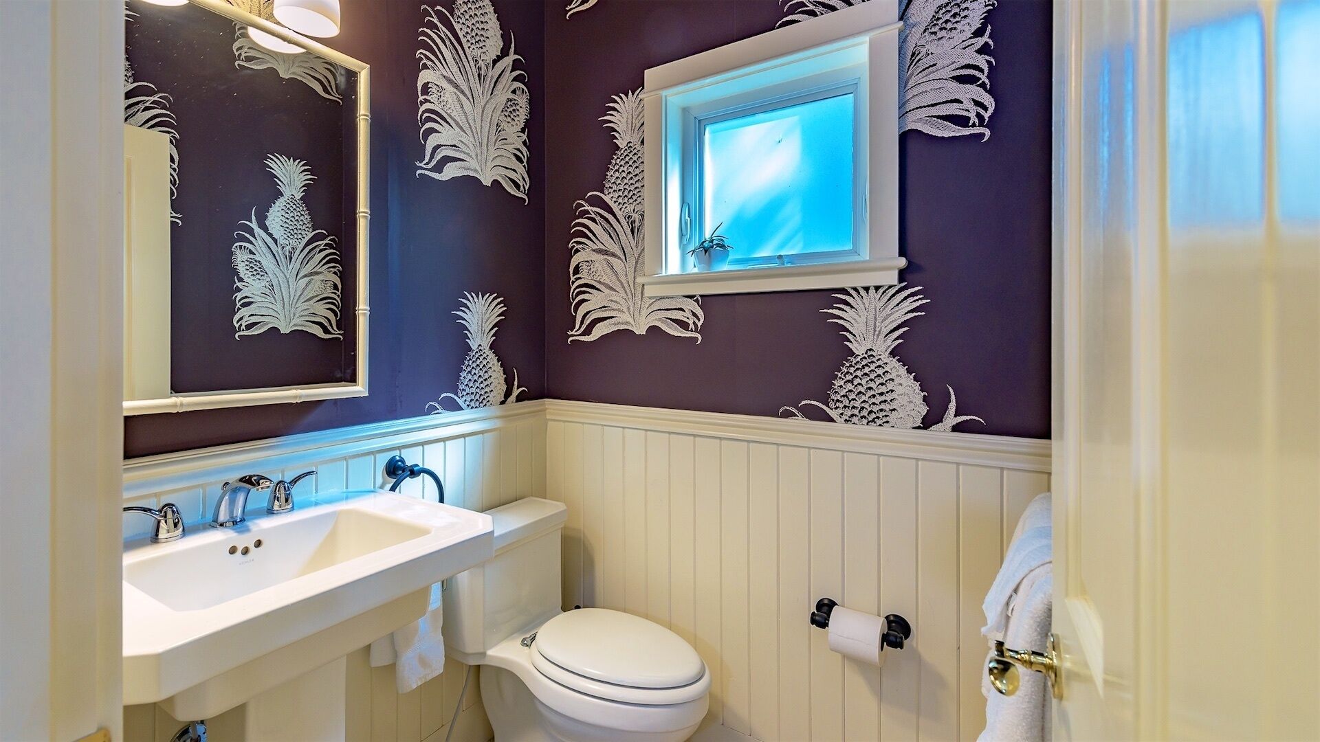 Une salle de bain avec un lavabo blanc, des toilettes et un miroir.