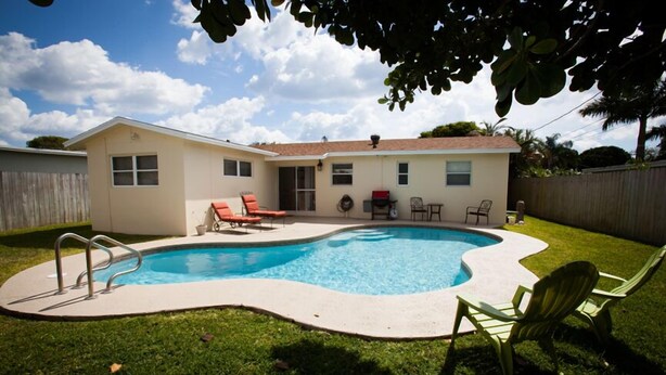 A backyard with a swimming pool, green lawn, and outdoor furniture.
