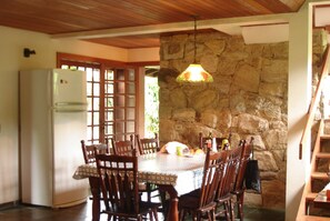 A dining area with a stone wall, wooden ceiling, and a table set for four.
