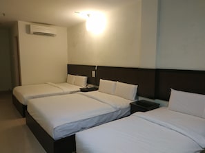 Et hotelværelse med to enkeltsenge, et sengebord med telefon og en aircondition på væggen.
