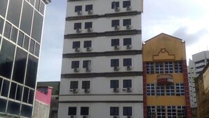 Un edificio de hotel de varios pisos con un letrero que dice "M HOTEL" en la parte superior.