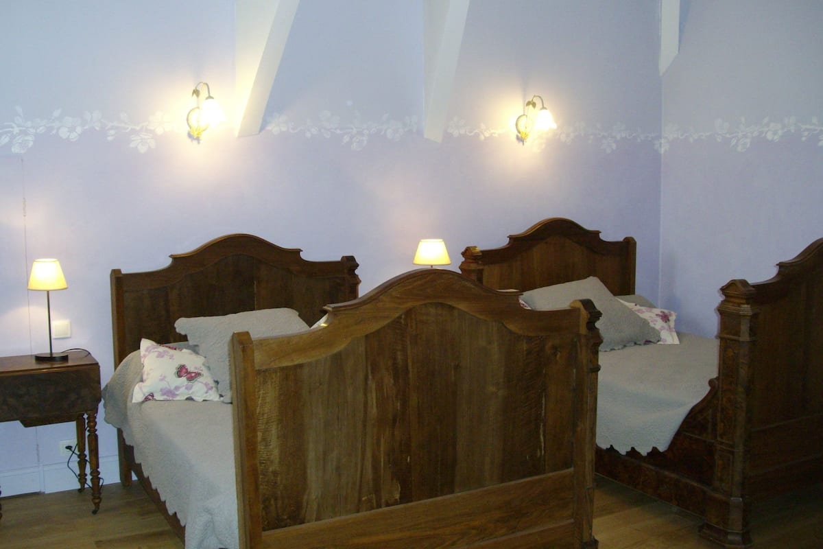 A bedroom with a wooden bed, two bedside lamps, and a floral-patterned wall.