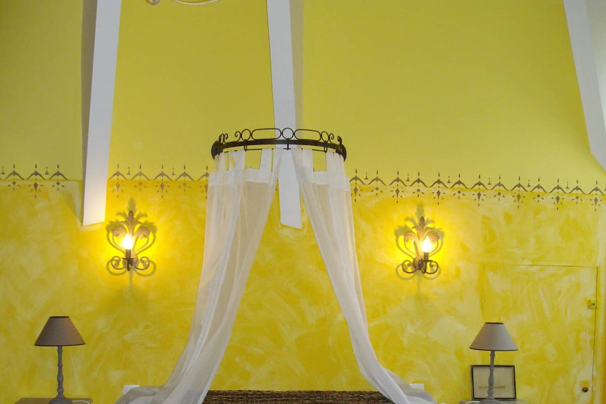 A bed with a canopy, two bedside tables with lamps, and a wall with decorative lighting.