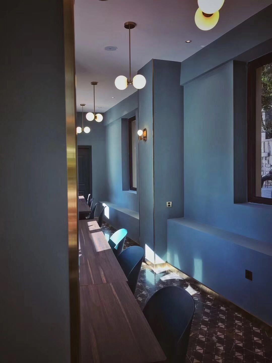 A conference room with a long table and chairs, blue walls, and pendant lighting.