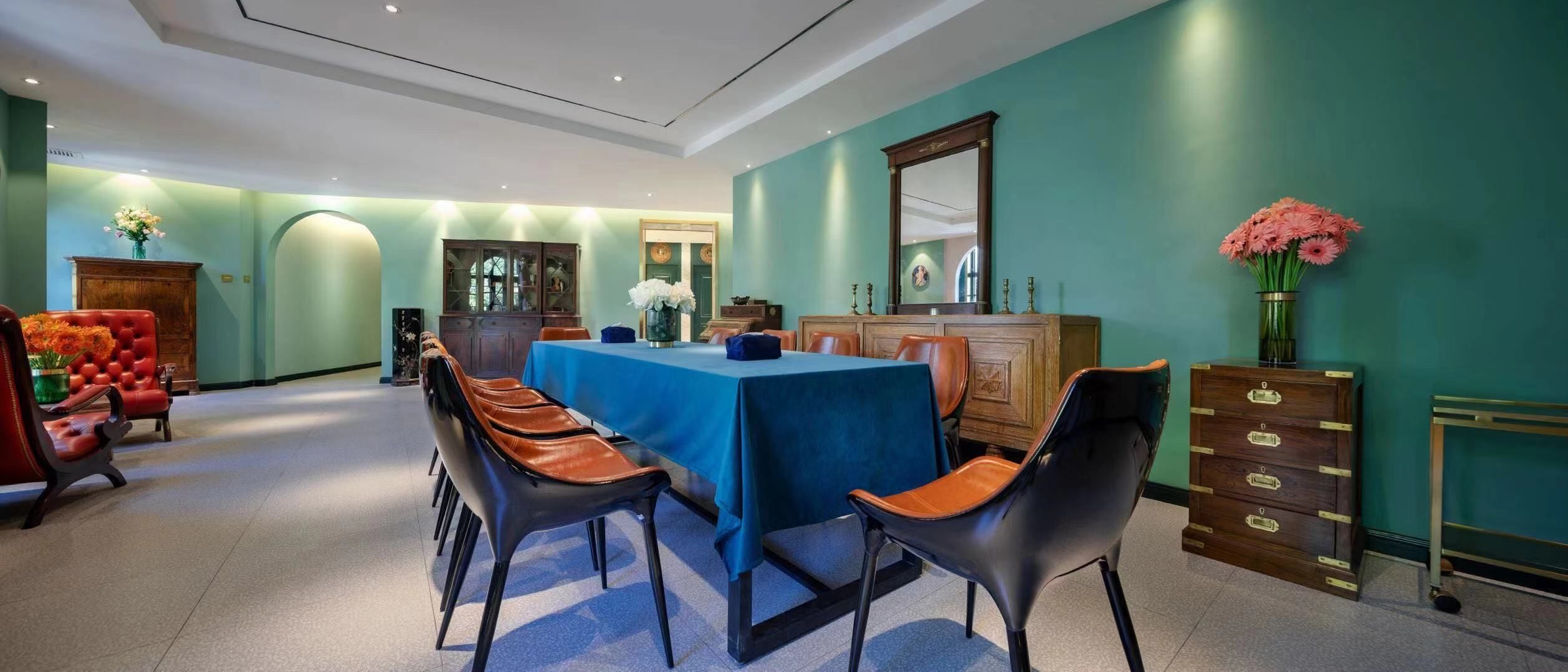A dining area with a blue table, leather chairs, and a wooden cabinet.