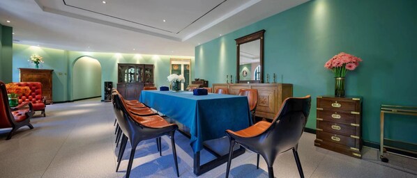 A dining area with a blue table, leather chairs, and a wooden cabinet.