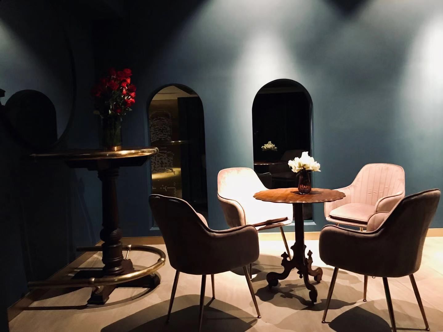 Una habitación tenuemente iluminada con una mesa redonda, dos sillas y un jarrón con flores.