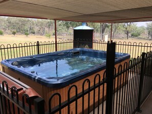 Ein Whirlpool mit Holzverkleidung und einem Metallzaun drumherum.