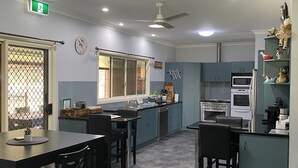 A modern kitchen with a dining area, featuring a central island, built-in appliances, and a ceiling fan. - Warwick Country Retreat Pets allowed  (Rosenthal Heights)