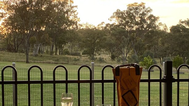 A hot tub with a glass of champagne and a bottle of wine, surrounded by a metal fence and trees in the background. - Warwick Country Retreat Pets allowed  (Rosenthal Heights)