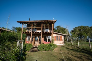 Enjoy a peaceful retreat with a front porch featuring a bench and hammock, overlooking a well-maintained lawn.