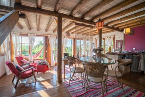 Relax in this rustic retreat with a round dining table, wicker chairs, and lush views.