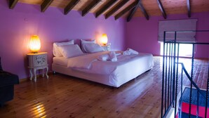 Een slaapkamer met een houten plafond, een bed met witte lakens, twee bedlampjes en een raam met een luxaflex.