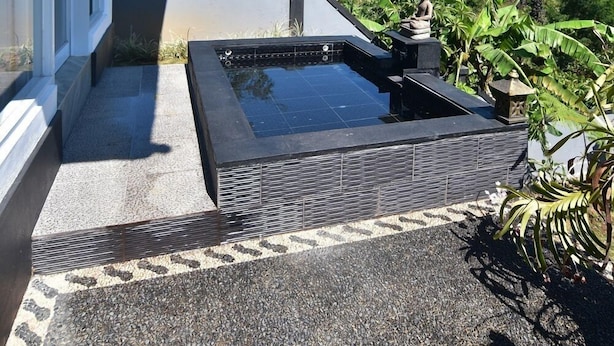 A modern outdoor area with a swimming pool, a stone pathway, and lush greenery. - Wanagiri Cosmic Nature Villa (Wanagiri)