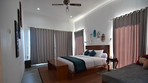 A bedroom with a large bed, a smaller bed, a wooden bench, a ceiling fan, and a view of the outside. - Wanagiri Cosmic Nature Villa (Wanagiri)