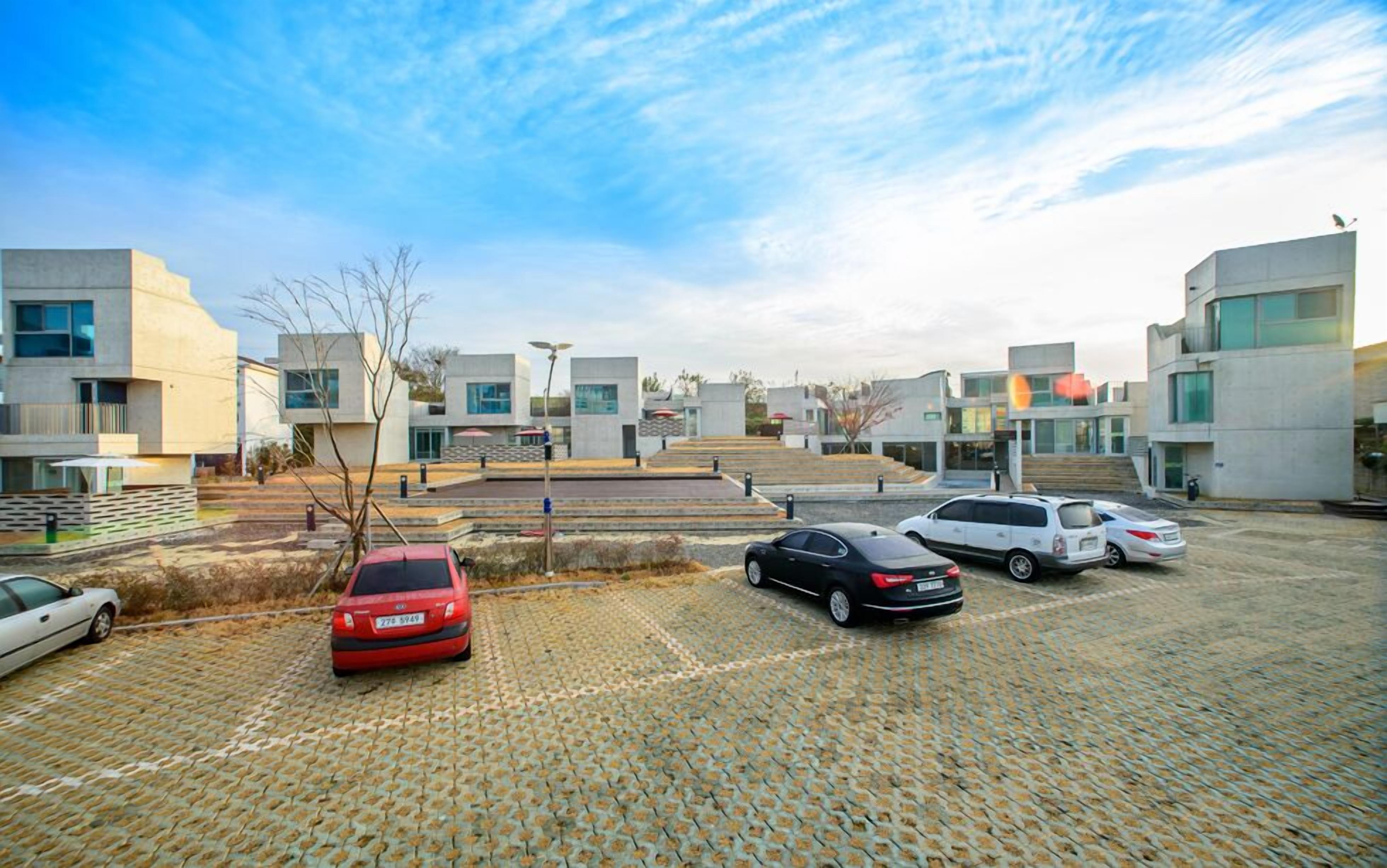 Un estacionamiento con varios autos, edificios modernos y cielo despejado.