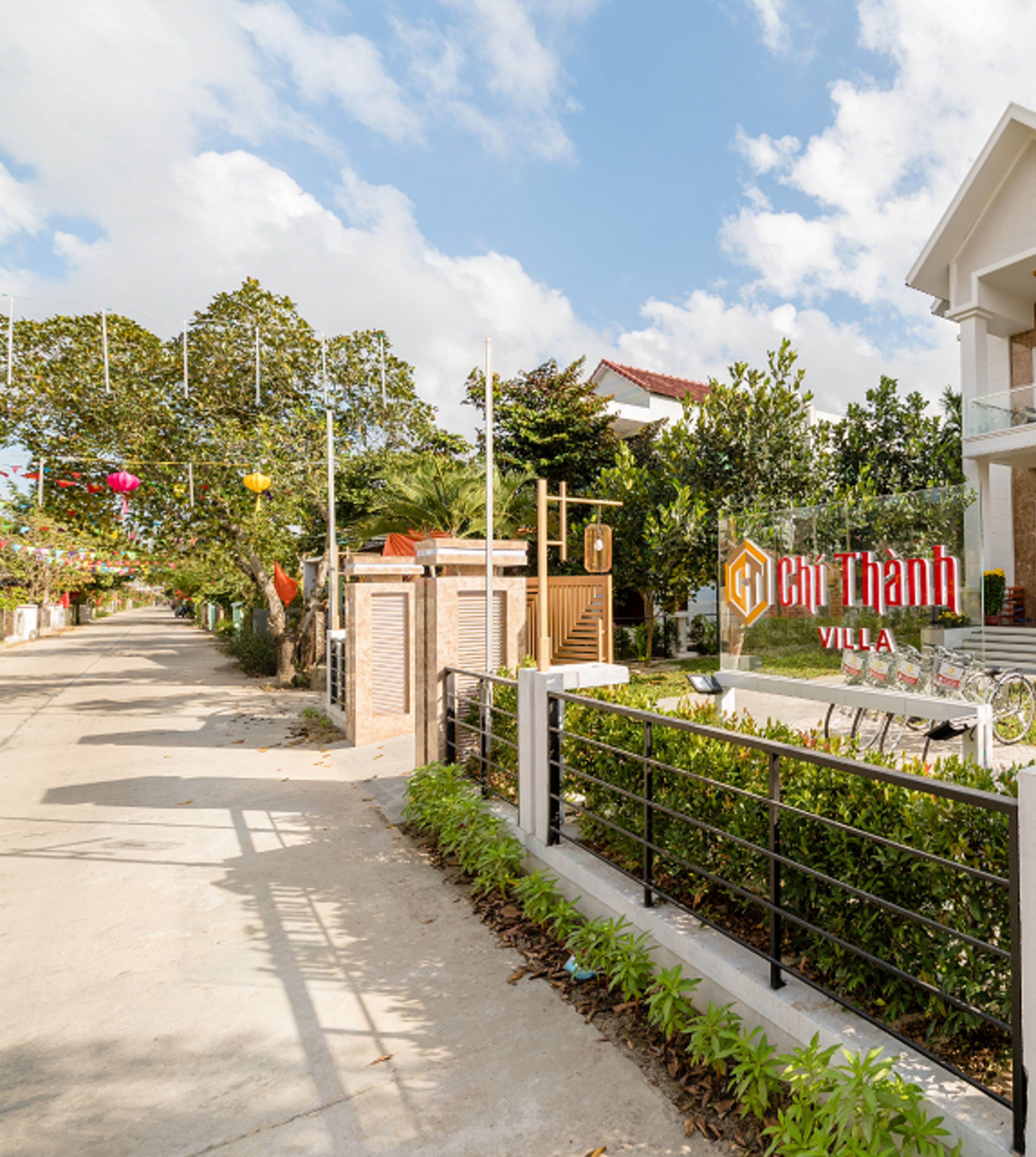 A villa complex with a gated entrance, a signboard, and a pathway leading to the buildings.