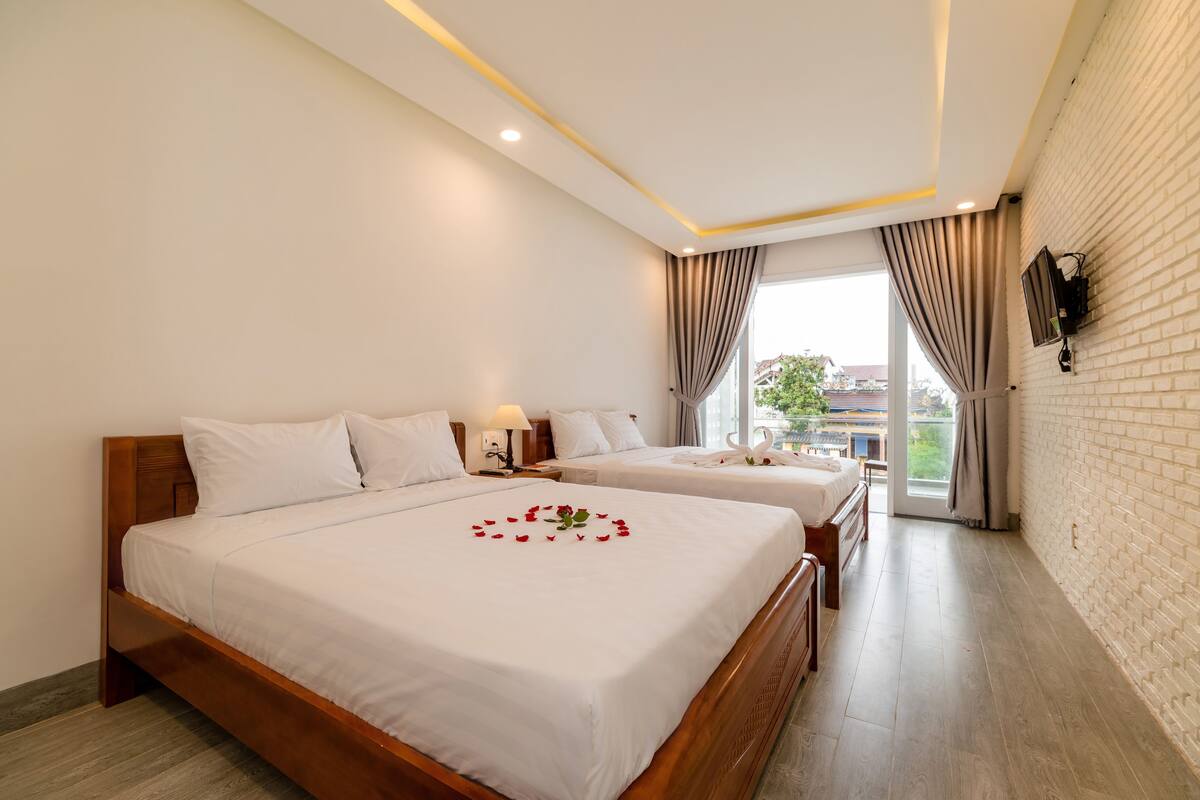 A hotel room with two beds, a large window, and a view of the outside.