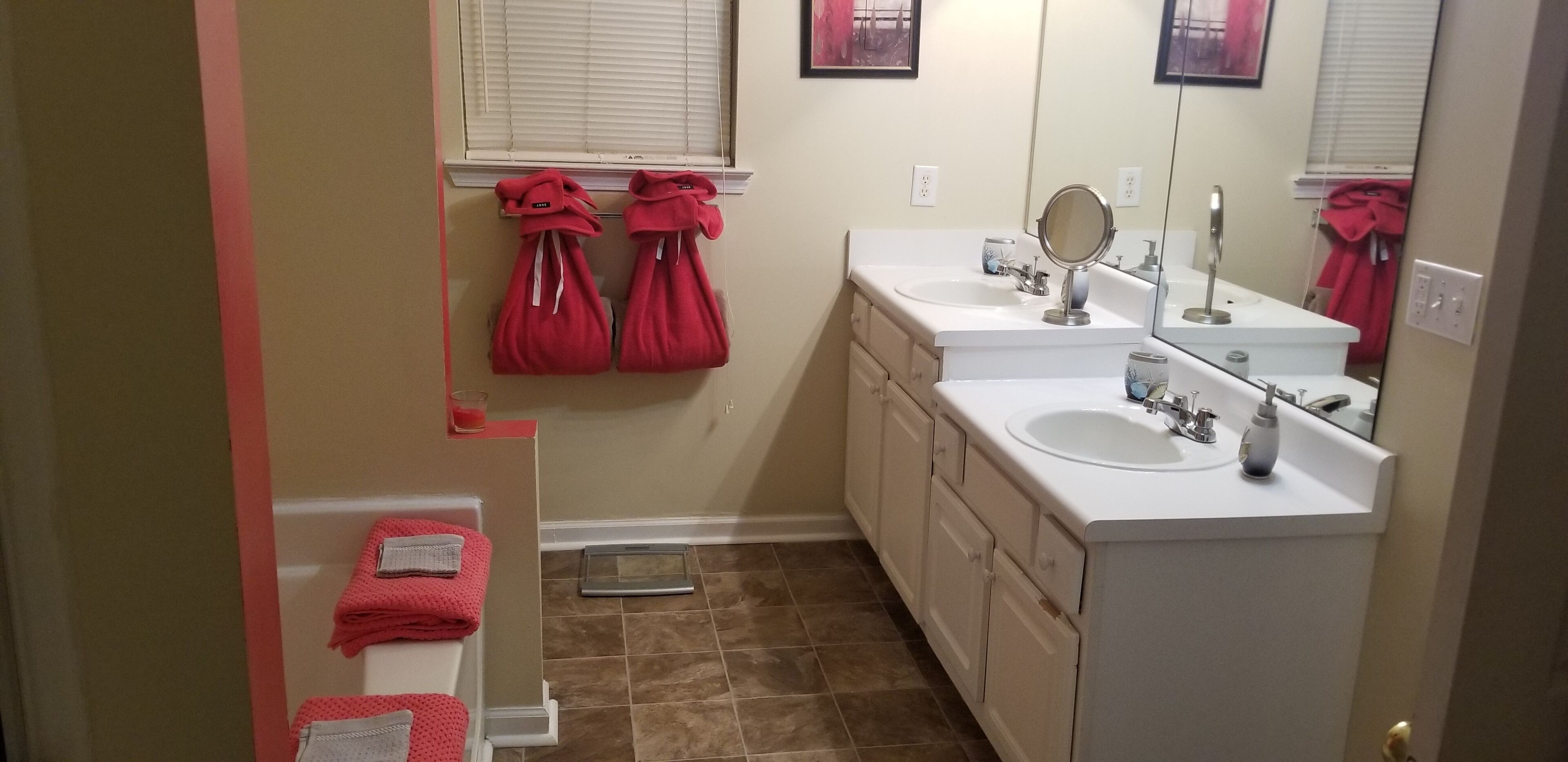Un baño con dos lavamanos, un espejo y toallas colgadas en la pared.