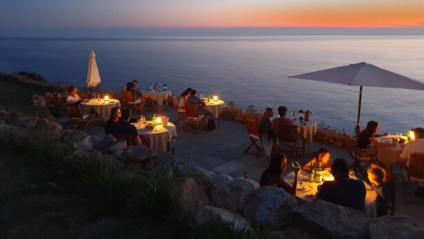 An outdoor dining area with tables and chairs, overlooking a body of water. - Faro di Punta Fenaio (Isola del Giglio)