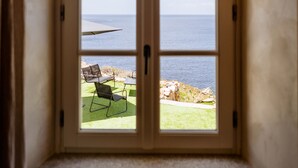A window with a view of the sea and a patio with chairs. - Faro di Punta Fenaio (Isola del Giglio)