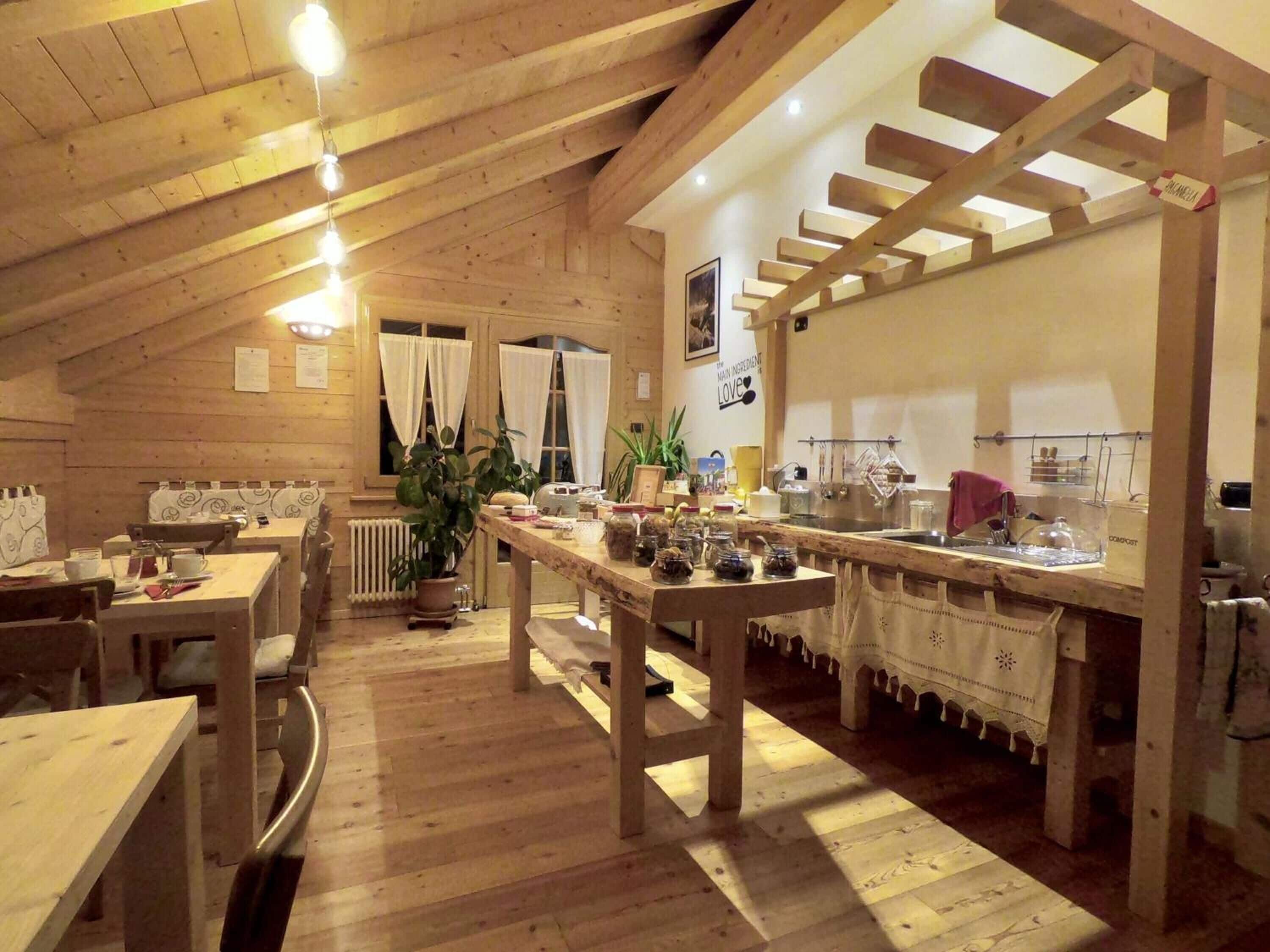 A rustic wooden interior with a dining area, kitchen, and a staircase.