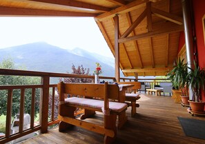 A wooden deck with benches and potted plants, overlooking a mountainous landscape. - Activity B&B (Spormaggiore)