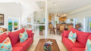 A spacious living area with red sofas, a wooden coffee table, and a staircase leading to an upper level.