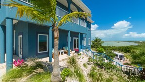 A two-story house with a balcony, a driveway, and a view of the ocean.