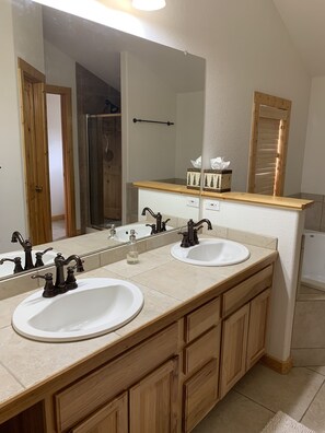 A bathroom with two sinks, wooden cabinets, a large mirror, and a towel rack.