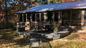 Un patio techado con mobiliario exterior, una fogata y un sendero de piedra.