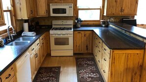 Una cocina con armarios de madera, un microondas, una estufa y un lavabo.