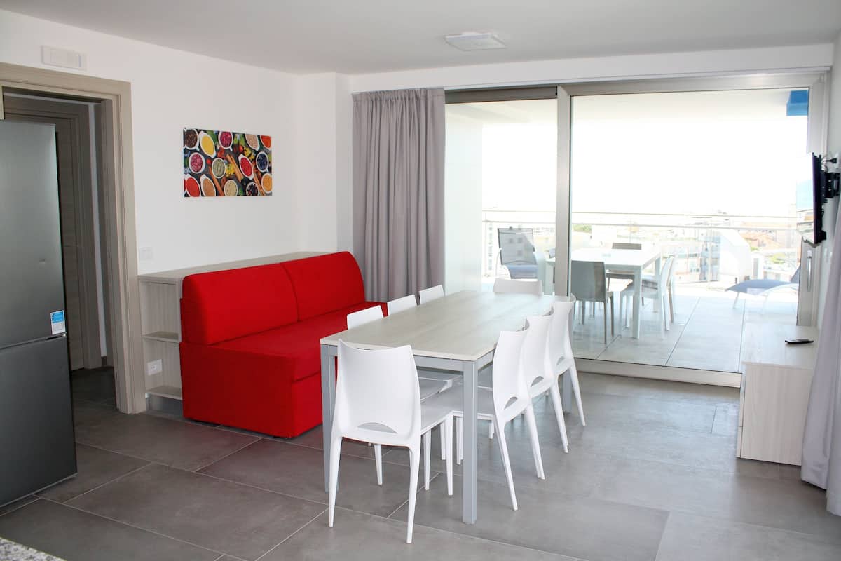 Une cuisine moderne avec un canapé rouge, des chaises blanches et une table à manger.