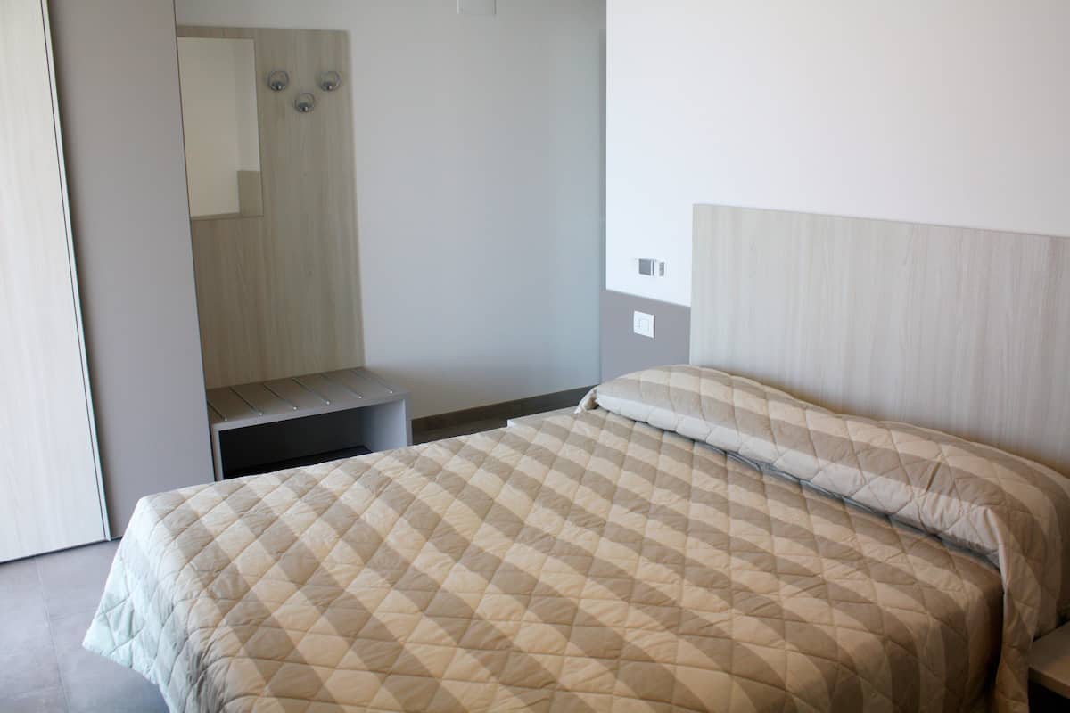 Une chambre à coucher avec un lit, une table de chevet et un miroir.