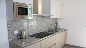 A modern kitchen with granite countertops, stainless steel appliances, and light wood cabinetry. - Appartamenti Nashira (Lignano Sabbiadoro)