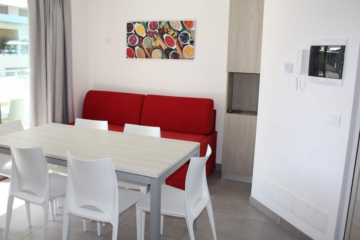 Un salon moderne avec un canapé rouge, une table à manger en bois et des chaises blanches.