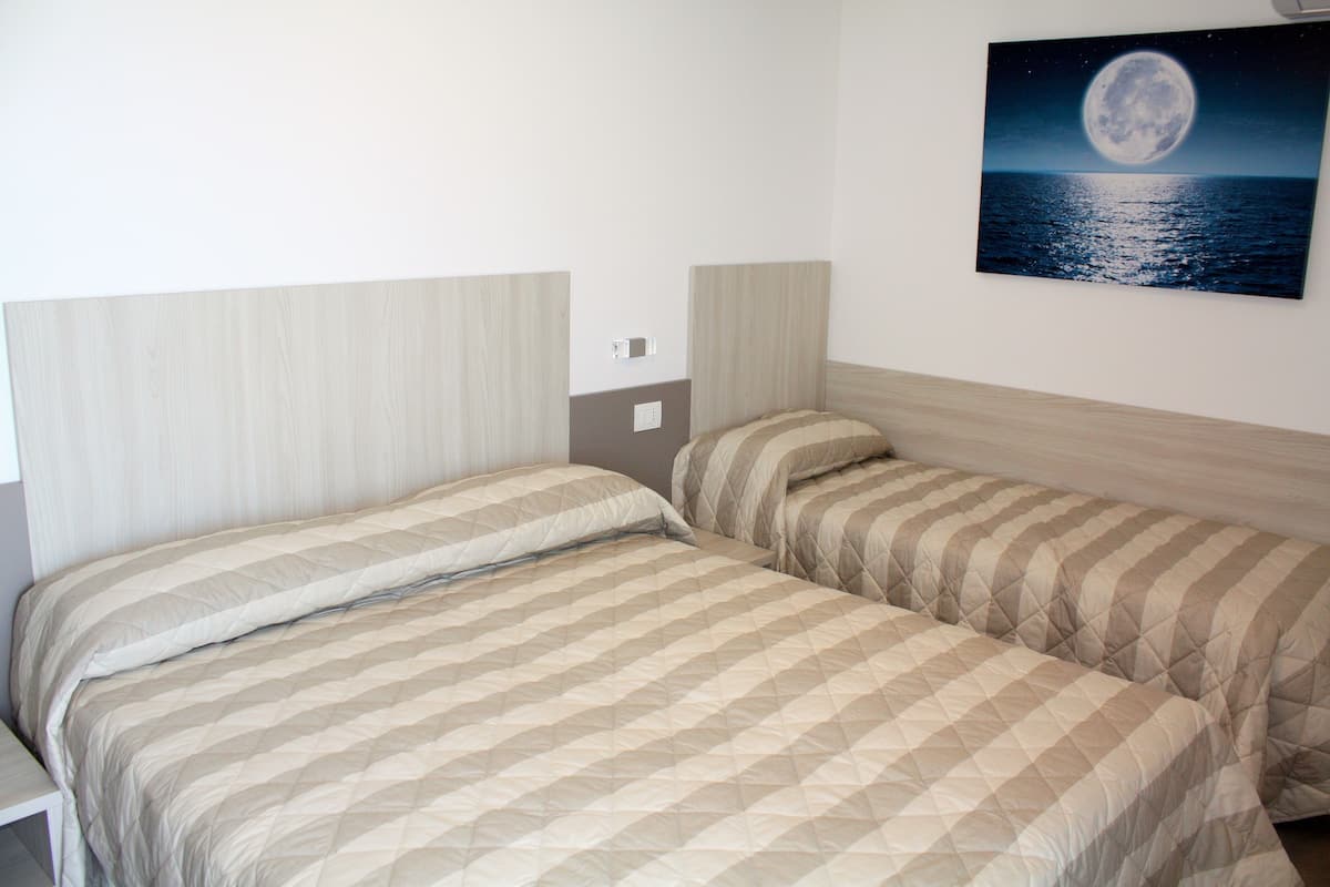 Une chambre double avec deux lits, une fresque représentant un ciel étoilé et une vue sur la mer.
