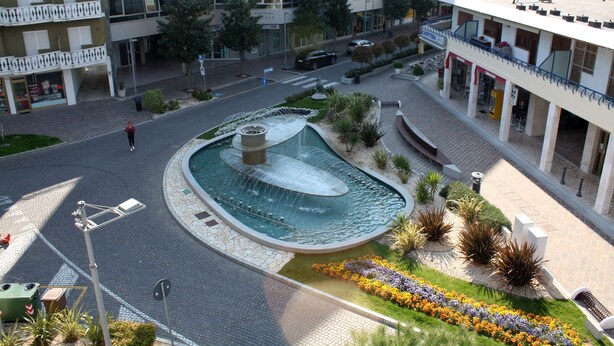 A modern building with a central courtyard featuring a water fountain and landscaped garden. - Appartamenti Nashira (Lignano Sabbiadoro)