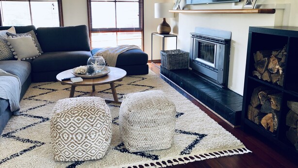 Un salon comprenant un canapé, des poufs, une table basse, une cheminée et un téléviseur fixé au mur.