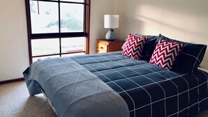 Une chambre à coucher avec un lit, une table de chevet, une lampe et une fenêtre.